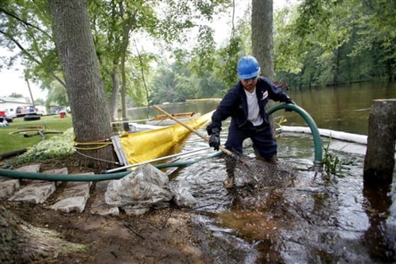 Raul Vervuzco of Eagle Services uses a suction hose to clean oil from atop the Kalamazoo River on Wednesday in a containment area in Augusta, Mich.